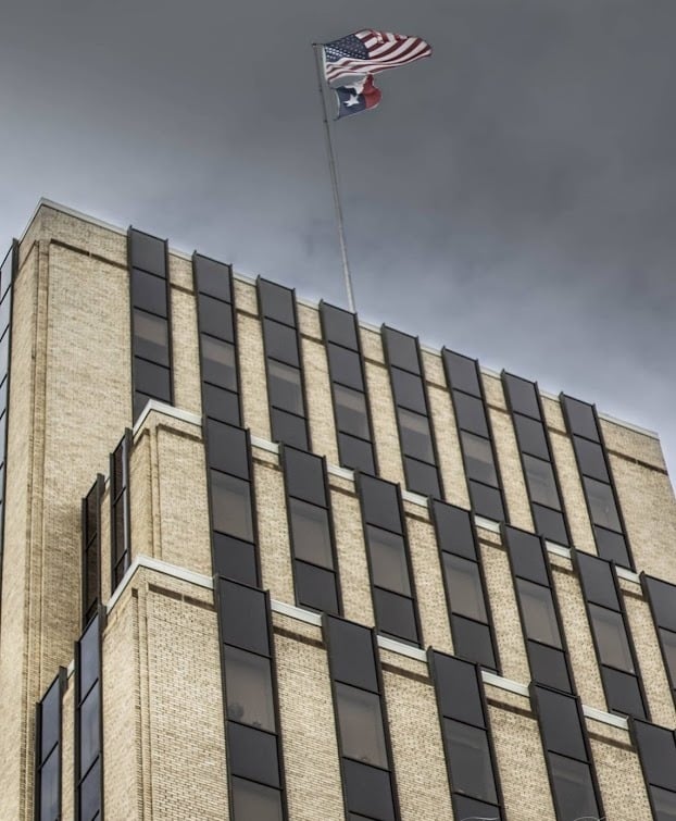 American and Texas flags flying atop a historic brick building in downtown Tyler, Texas